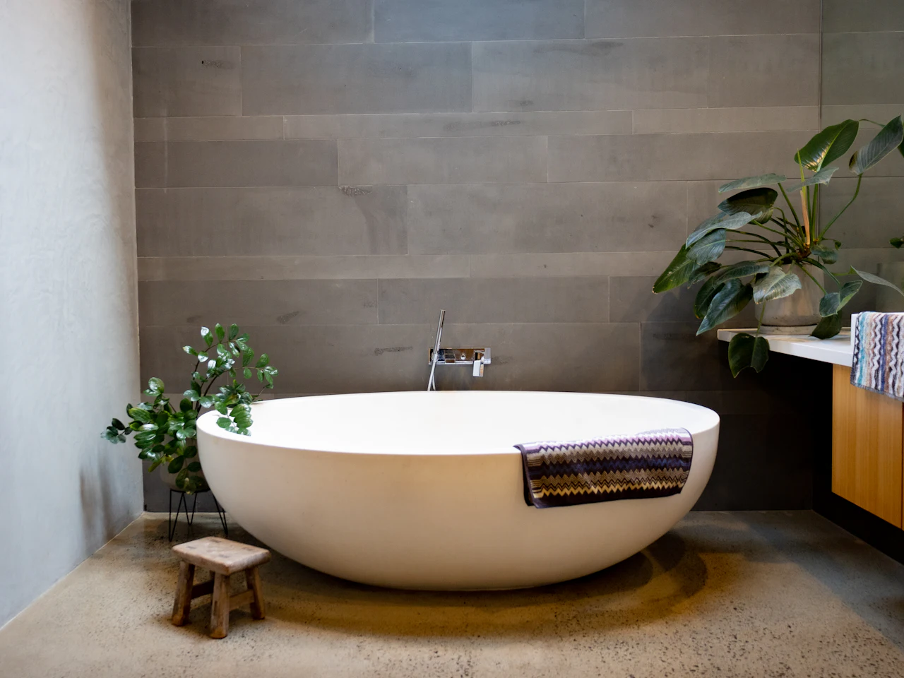 Bathroom with a freestanding tub, plants and oak vanity